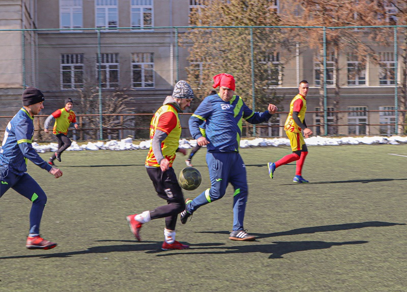 Na zdjęciu widać zawodników walczących o piłkę, na syntetycznej murawie.