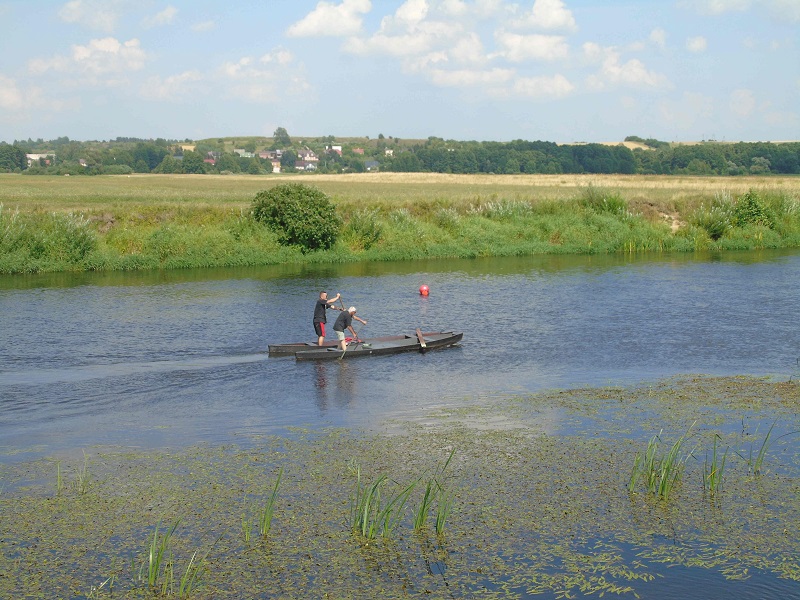 zdjęcie przedstawiające dwóch zawodników płynących na pychówce na rzece Narew, w tle pola i panorama na Piątnicę