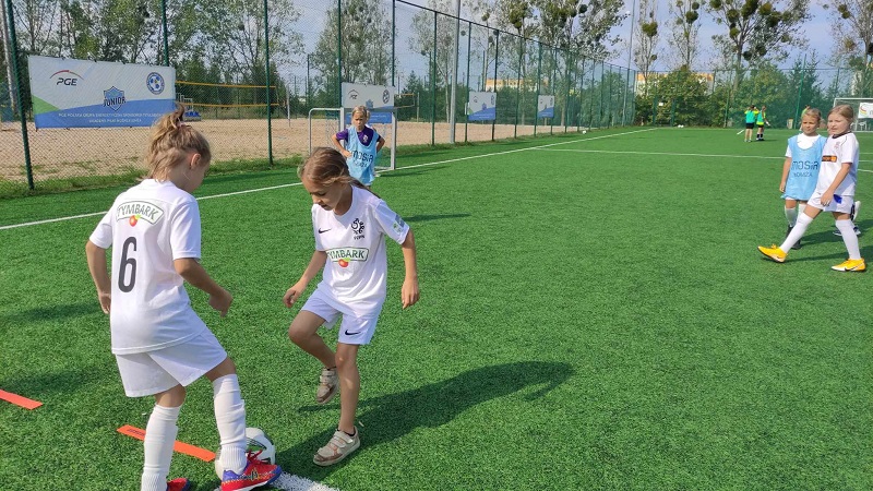 zdjęcie młodych zaqwodniczek grających w piłkę nożną na murawie boiska Orlik