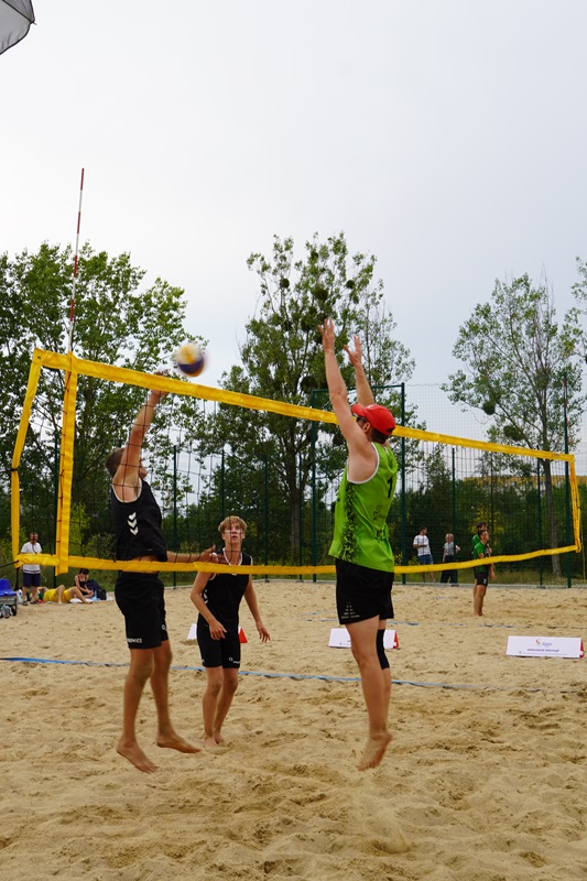 Zdjęcie przedstawia3 zawodników grających w siatkówkę plażową