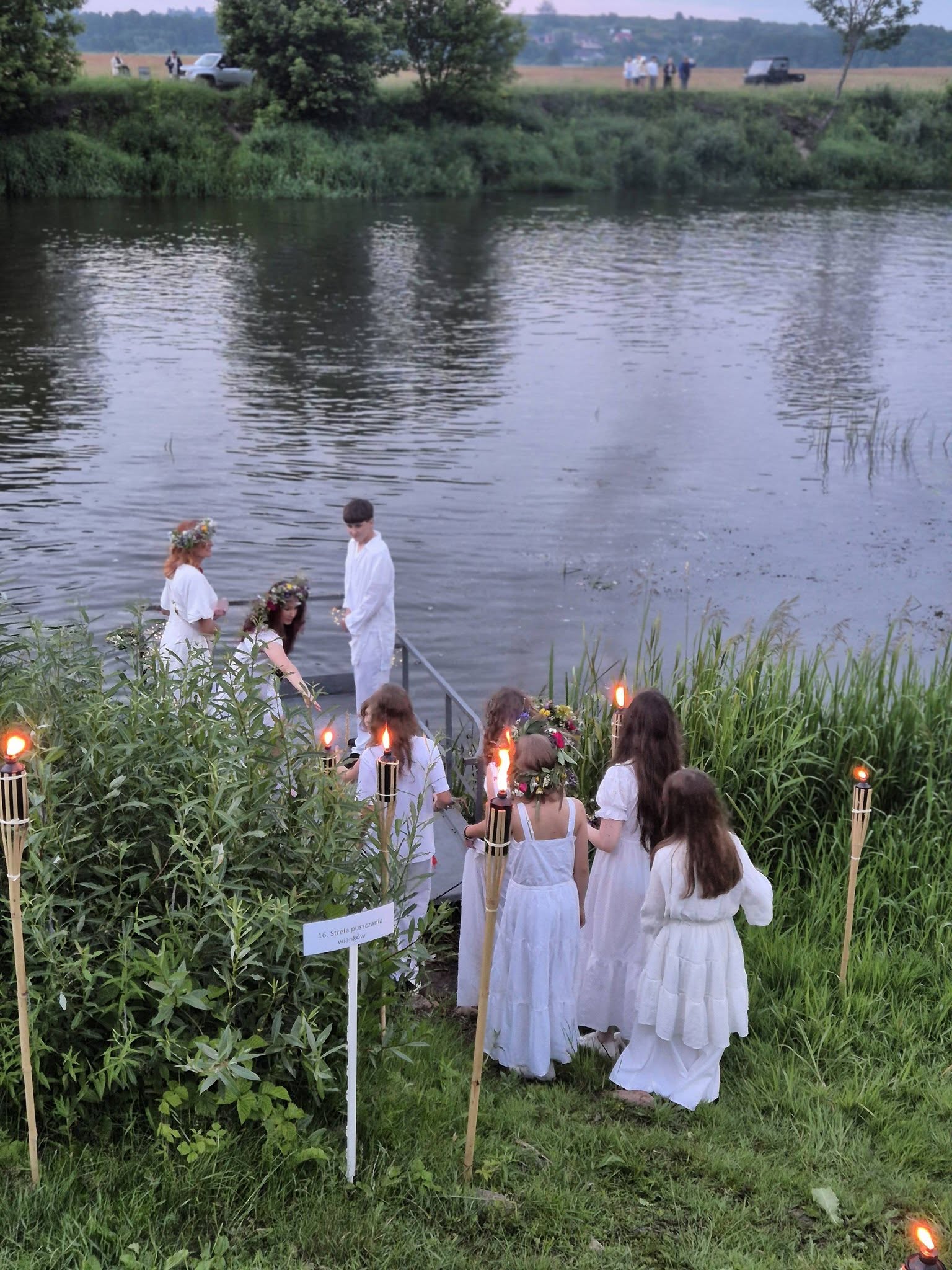 grupa osób puszczająca wianki nad rzeką
